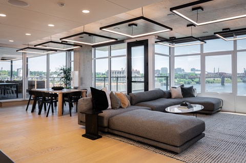 A modern living room with a large grey sofa and a view of the city.