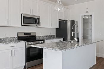 A kitchen with white cabinets and granite countertops.