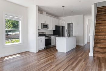 A kitchen with white cabinets and a wooden floor.