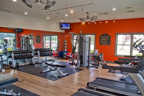 A gym with orange walls and a variety of equipment.