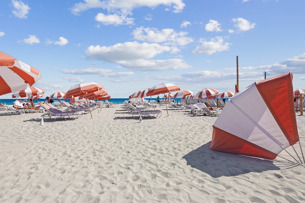 Beach scene near The Anamar at Collins Park in Miami Beach, Florida, featuring umbrellas and lounge chairs, located in a pet-friendly apartment community in the 33139 area.