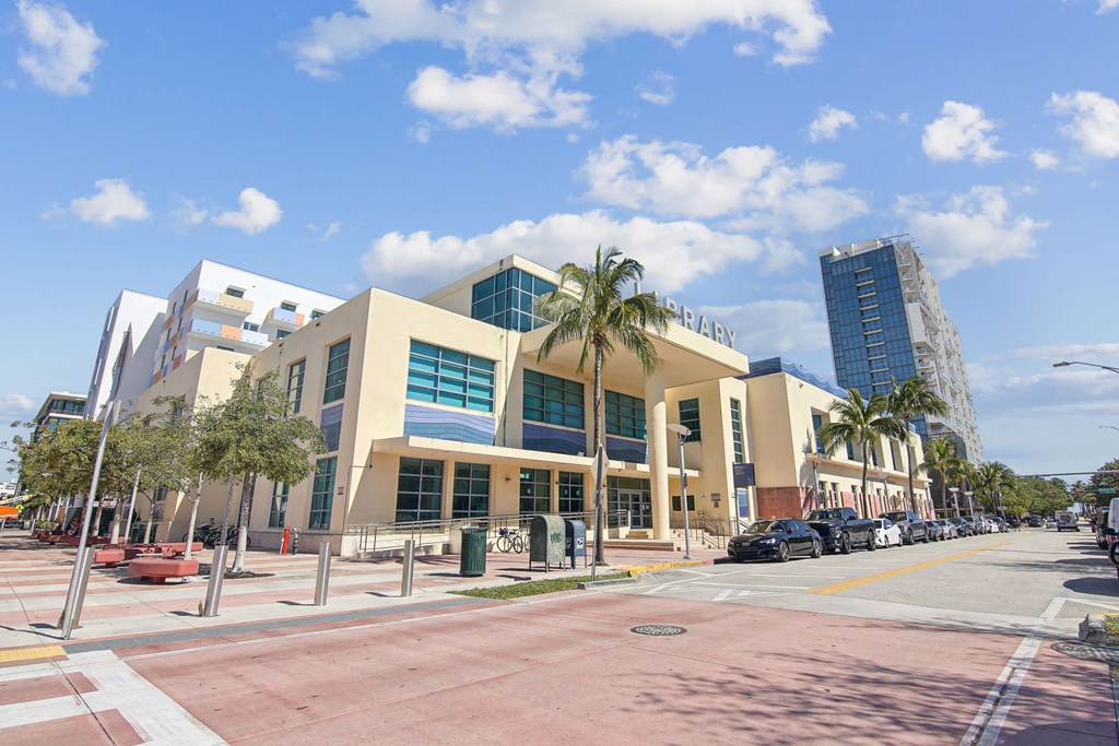 Downtown Miami, FL Apartments – The Anamar at Collins Park – A library with a glass facade and palm trees in front.