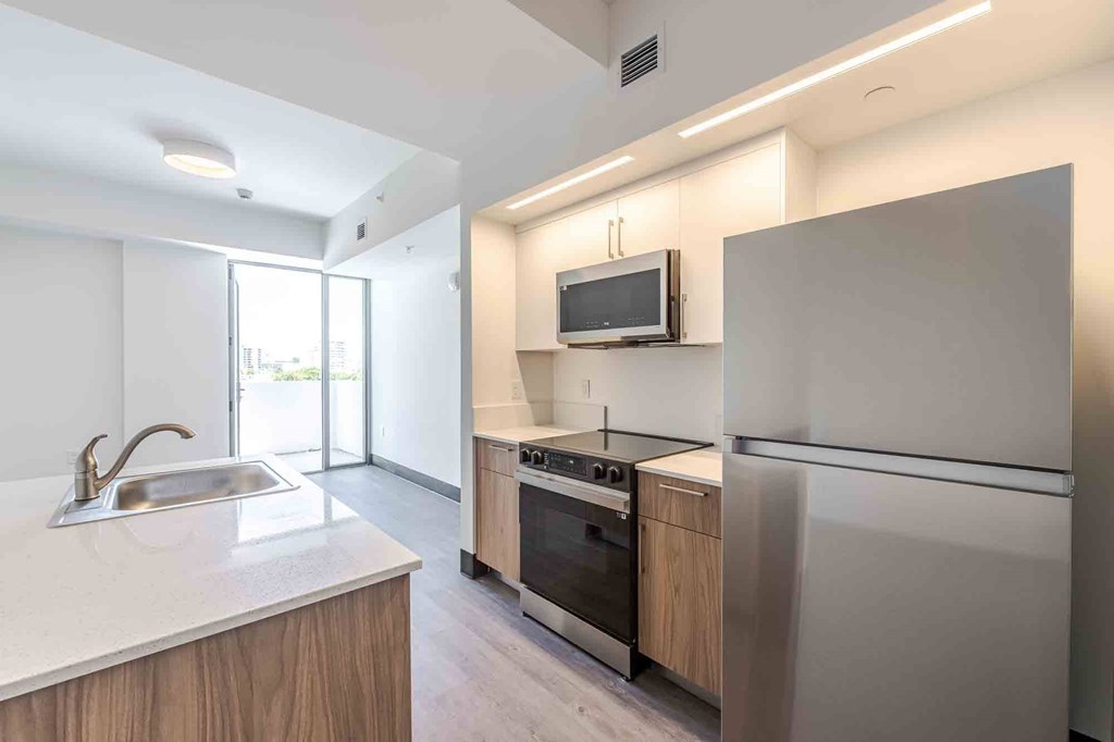 Pet-friendly home featuring a modern kitchen with a built-in microwave, refrigerator, and stove in a Miami Beach apartment.