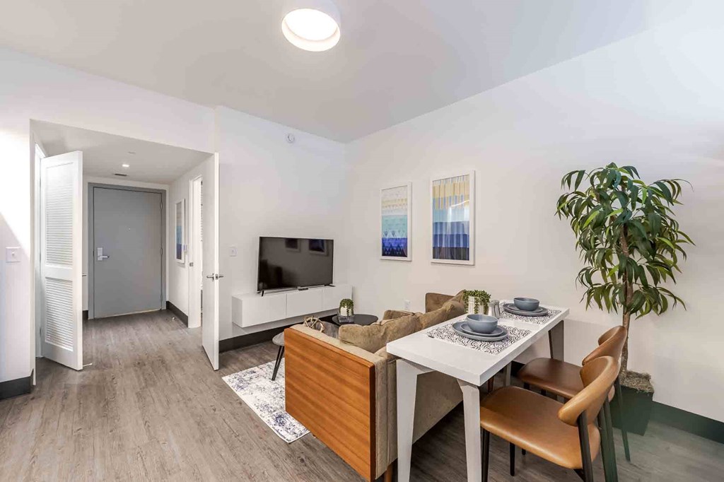 Spacious living room in a pet-friendly Miami Beach apartment featuring wood-style vinyl plank flooring, modern design, and natural lighting.