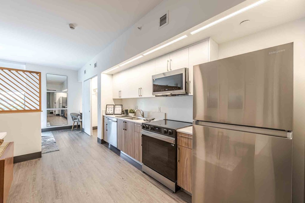 Modern kitchen in a pet-friendly Miami Beach apartment featuring energy-efficient appliances, sleek countertops, a built-in microwave, refrigerator, and dishwasher in an open-concept layout.