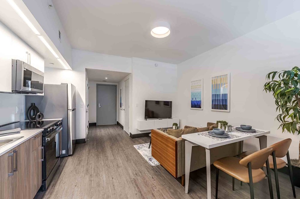 Open-concept living room, dining area, and kitchen in a modern, pet-friendly Miami Beach apartment featuring energy-efficient appliances, sleek finishes, and natural lighting.