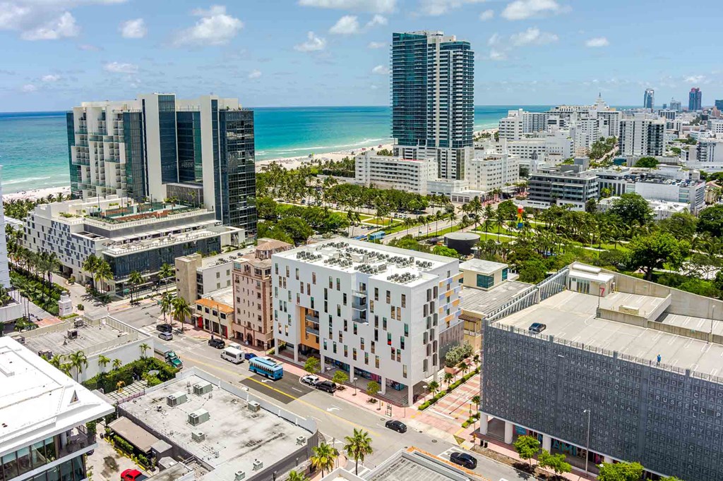 High-angle view of a modern, pet-friendly Miami Beach apartment complex surrounded by city infrastructure.