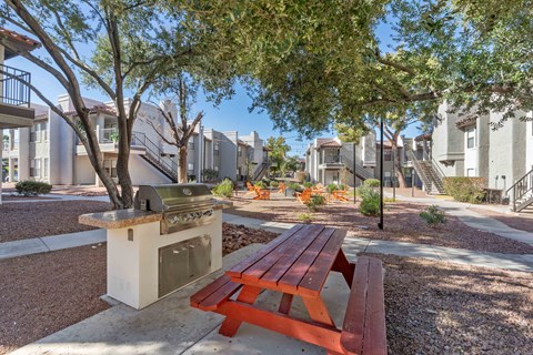 a picnic table and barbecue grill in a park with trees
