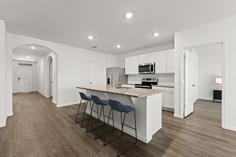 A kitchen with white cabinets and a countertop with a bar stool.