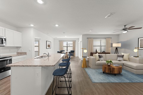 A modern kitchen with a bar area and a living room with a couch.