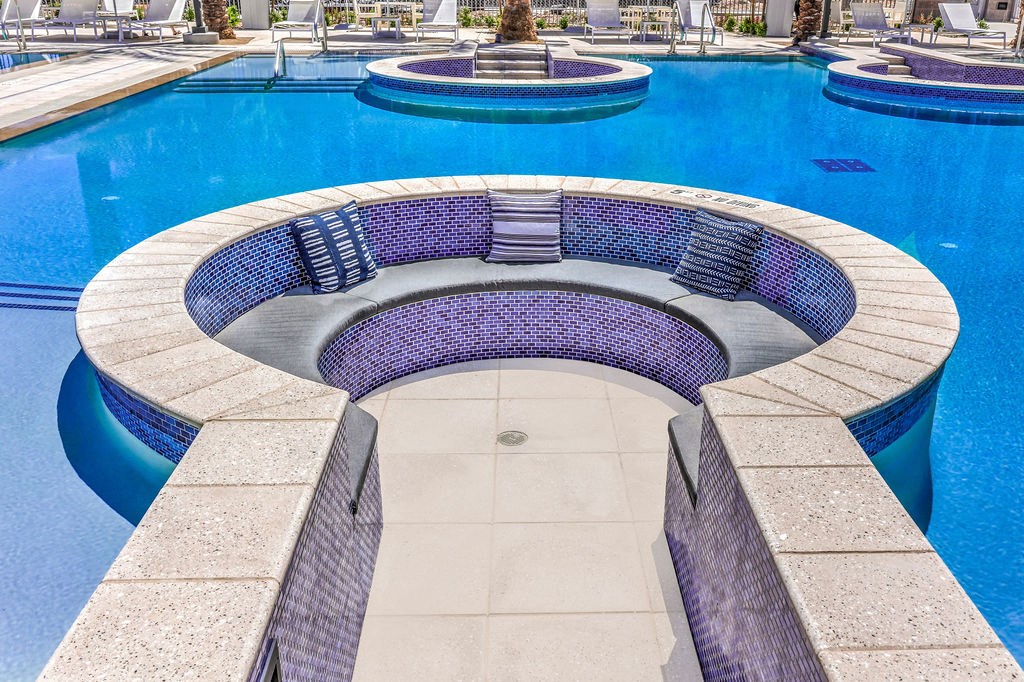 a swimming pool with a stone bench and a fountain in the background