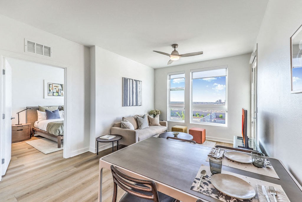 a dining area with a table and chairs, a couch with a bed in the background and