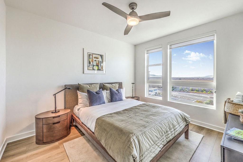 a bedroom with a large window and a ceiling fan