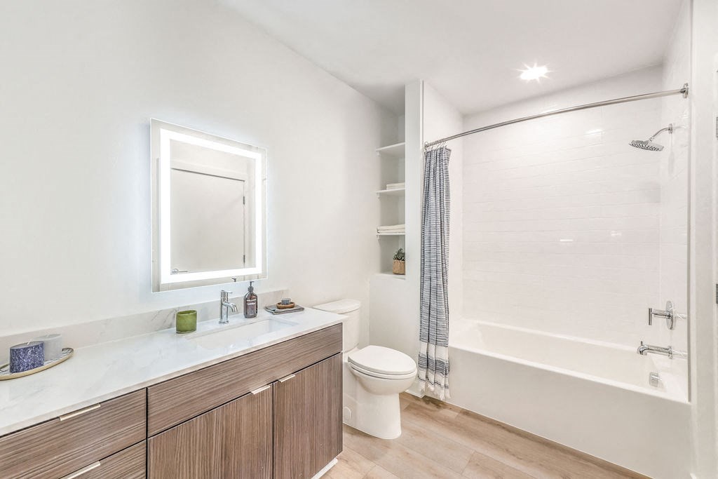 a bathroom with white walls and wood floors