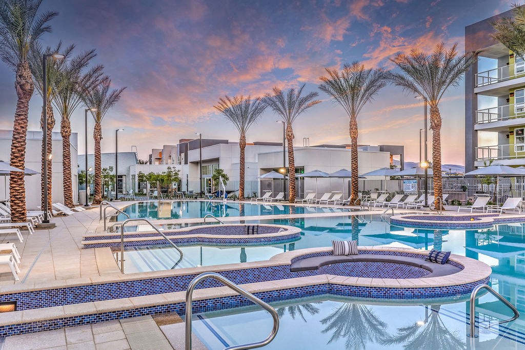 a resort style pool with chaise lounge chairs and palm trees