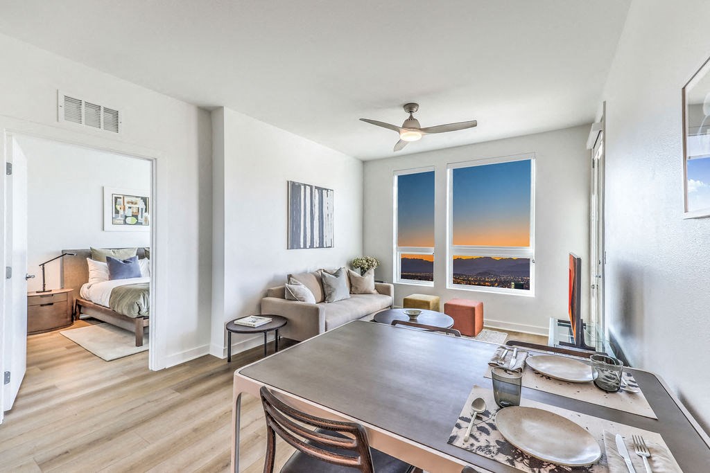 a dining area with a table and chairs, a couch with a bed in the background and