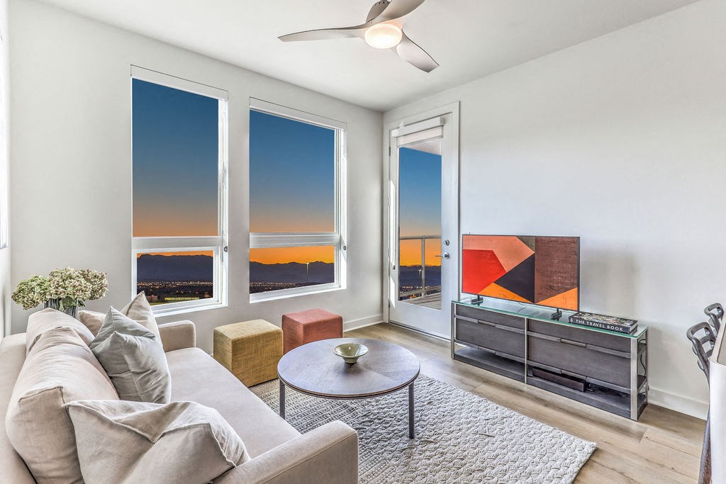 a living room with white walls and a large window with a view of the city