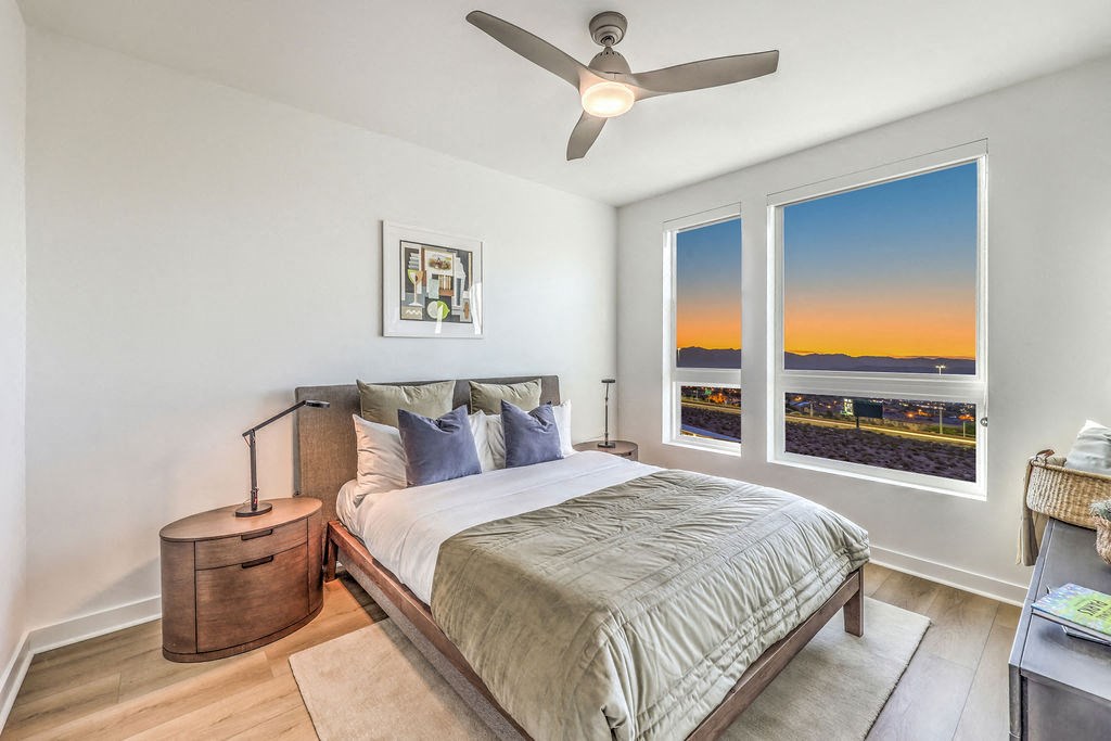 a bedroom with a large window and a ceiling fan