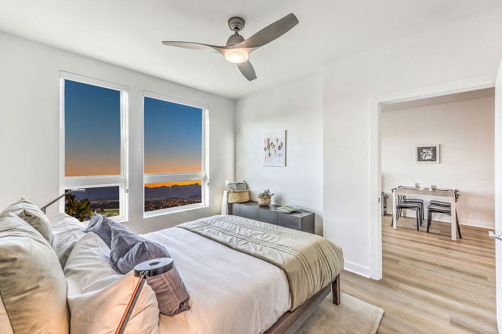 a bedroom with a large window and a ceiling fan