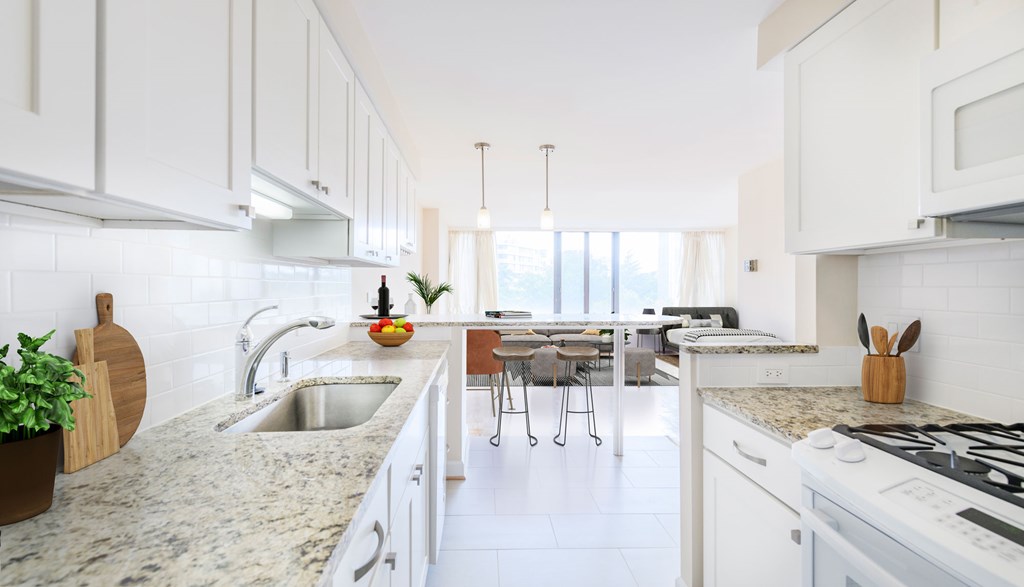 A kitchen with white cabinets and a marble countertop.