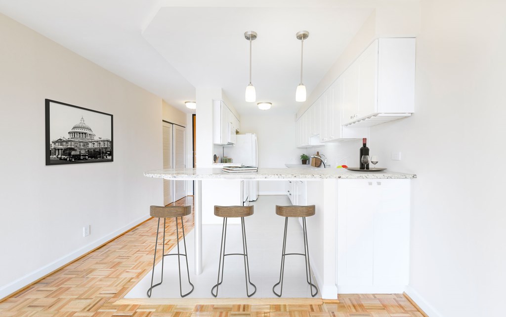 A kitchen with white cabinets and a framed picture of a building on the wall.