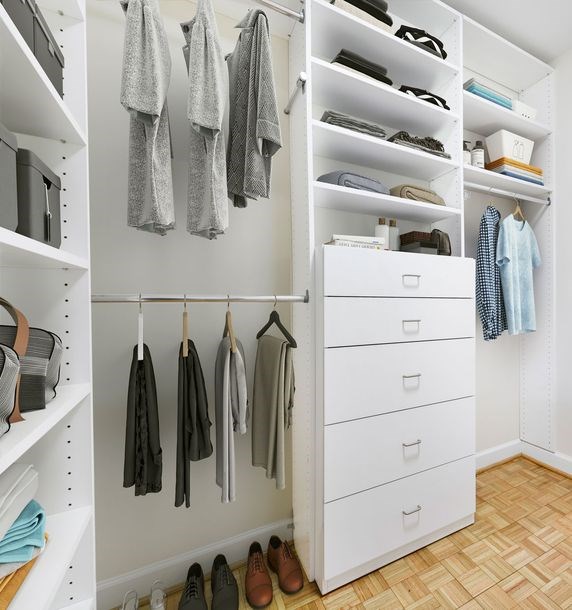A white closet with clothes and shoes.