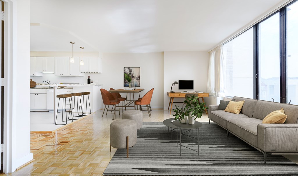 A modern living room with a grey sofa, wooden floors, and a kitchen area in the background.
