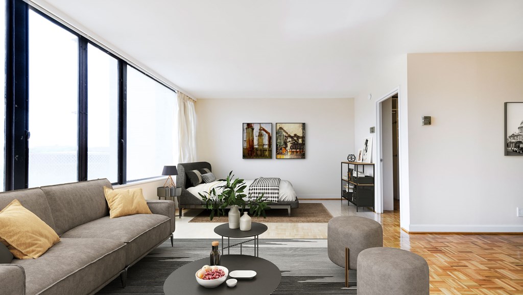A living room with a grey couch, a coffee table, and a large window.