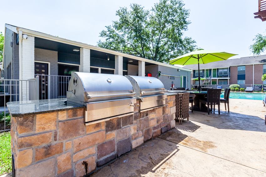 our covered patio has a grill and a bar with chairs and umbrellas
