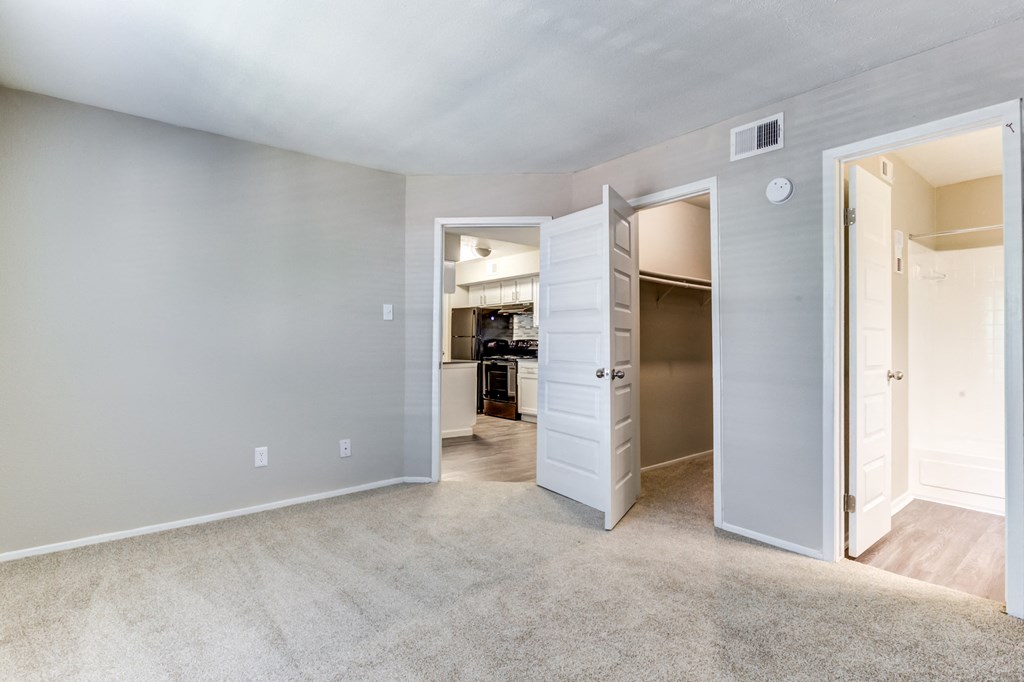 a bedroom with a closet and an open door to a kitchen