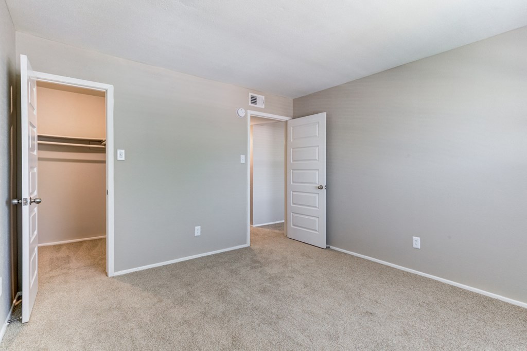 an empty bedroom with a closet and an open door