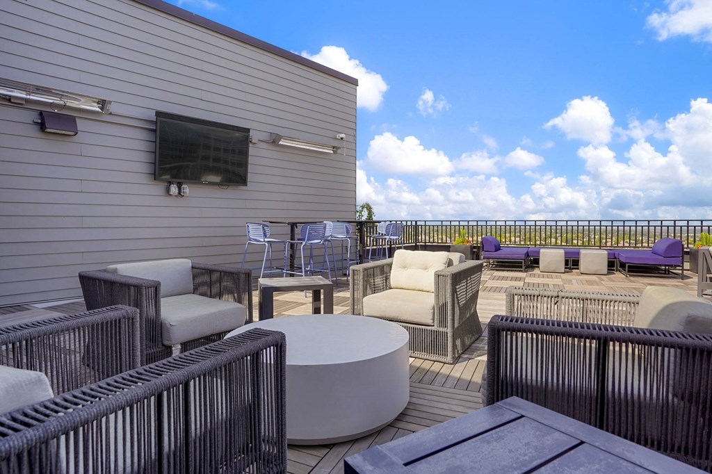 a patio with chairs and tables and a building with a sky background