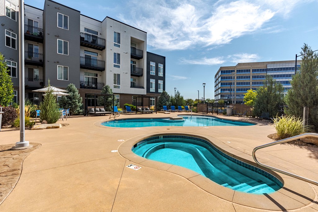 our apartments have a pool and hot tub with an apartment building in the background