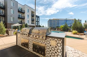 an outdoor grilling area with an apartment building in the background
