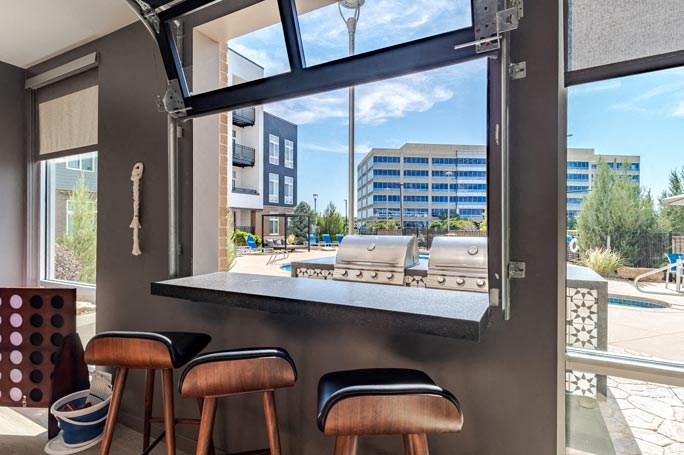 a bar with three stools in front of a large window