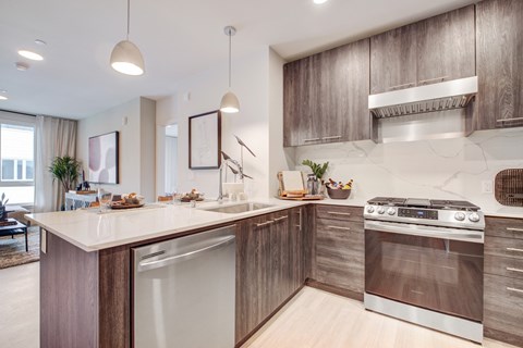 an apartment kitchen with stainless steel appliances and wooden cabinets