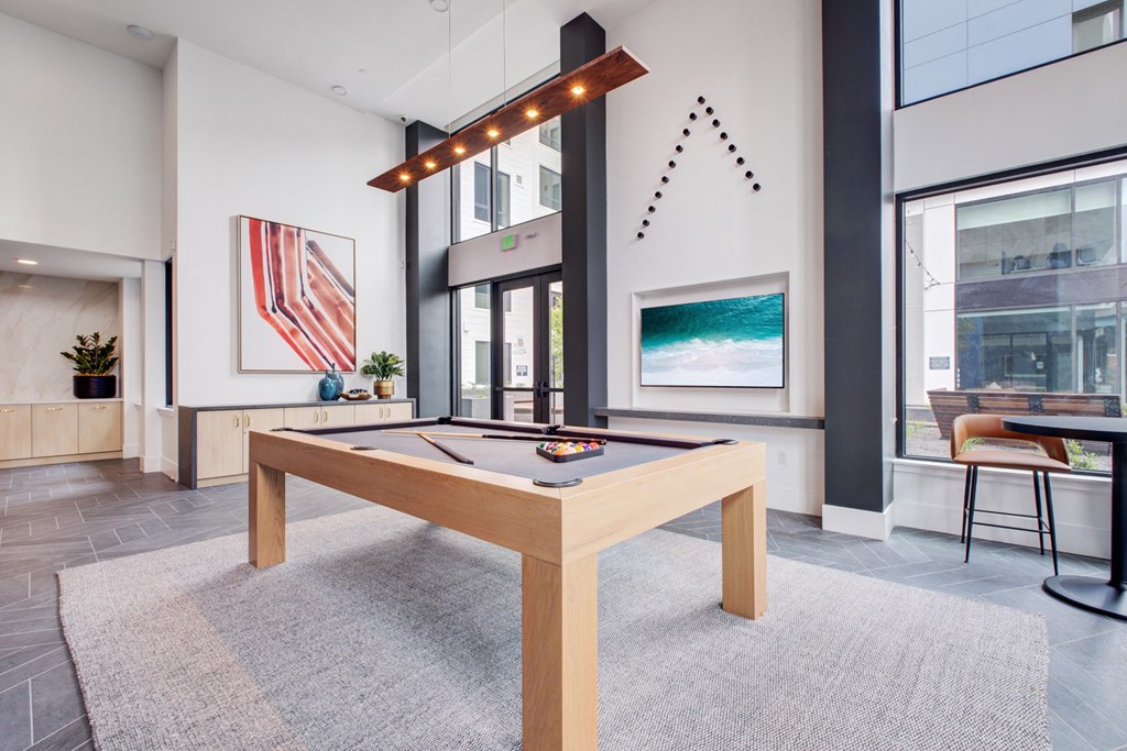 a billiards table in the clubhouse of a building with large windows