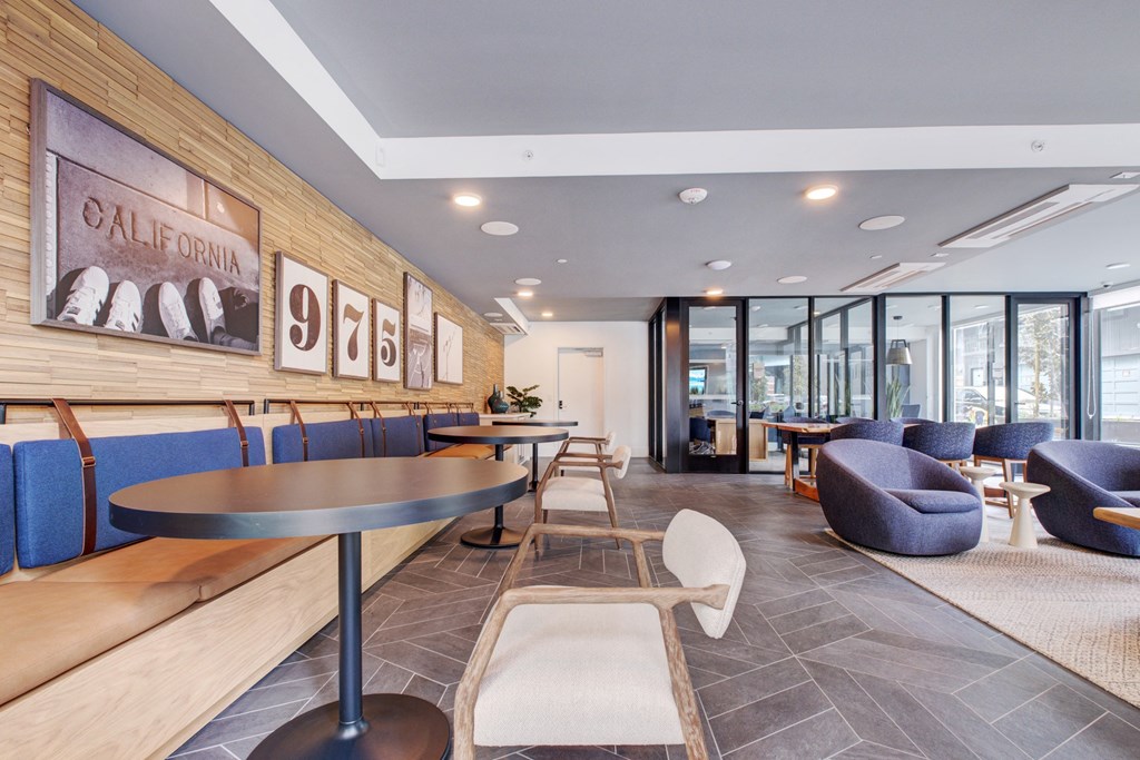 a lounge area with couches tables and chairs and a wall of windows