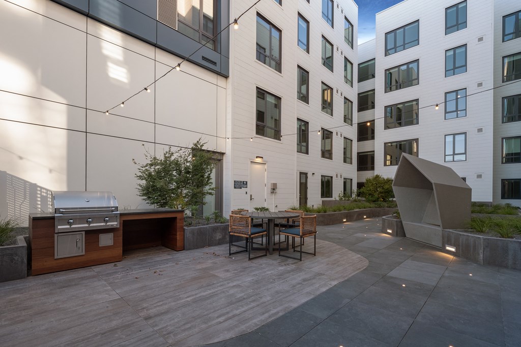 a patio with a grill and a table in front of a building