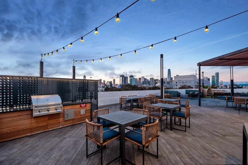 a rooftop patio with tables and chairs and a city skyline