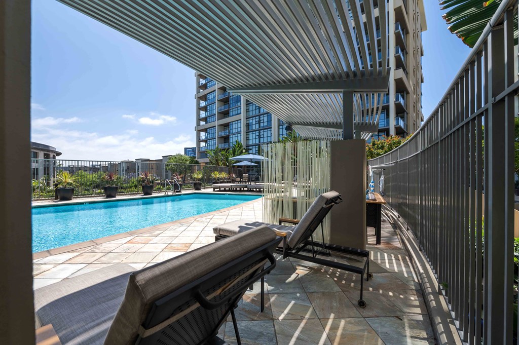 Irvine, CA, Apartments for Rent - Astoria at Central Park West - Gated Pool with Lounge Chairs, Umbrellas, and Potted Plants.