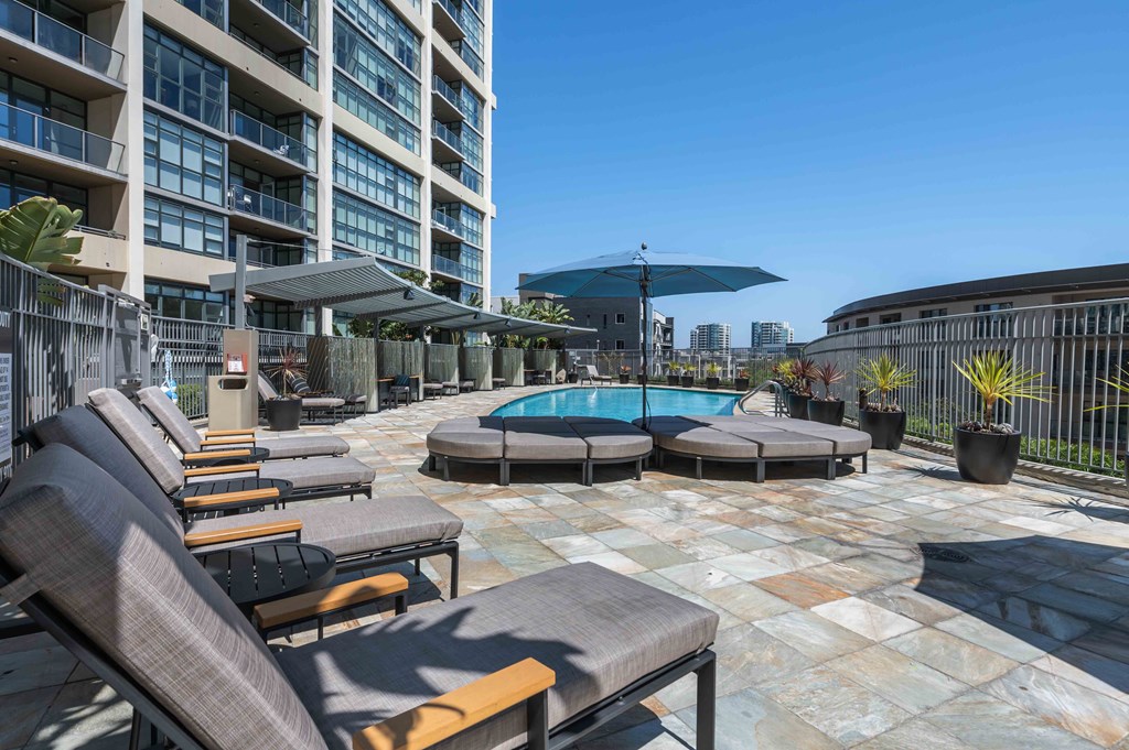 a resort style pool with lounge chairs and umbrellas in front of a building