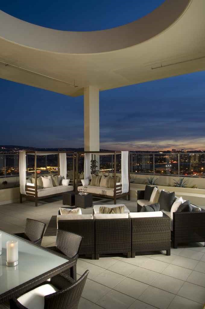 A patio with a table and chairs overlooking a city at night.