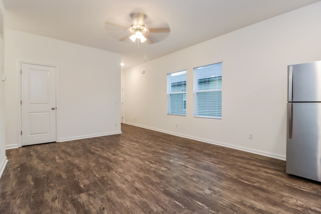 A room with a ceiling fan and a refrigerator.