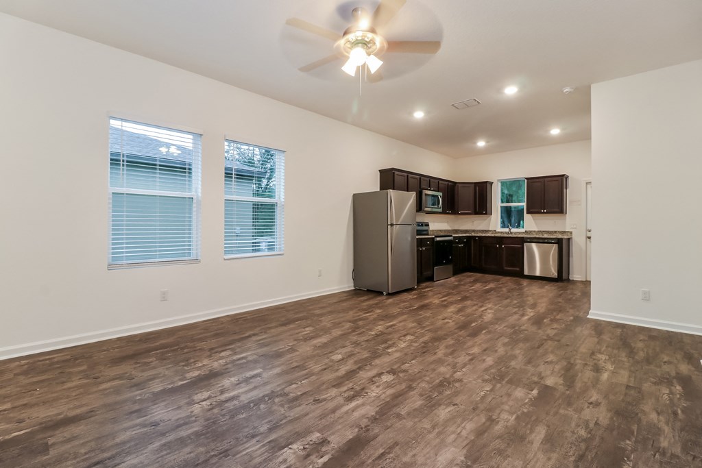 A room with a ceiling fan and wooden flooring.