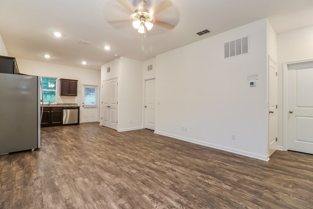 A spacious room with a ceiling fan and wooden flooring.