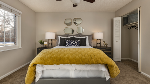 A bedroom with a bed covered in a yellow comforter.