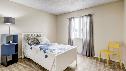 A bedroom with a white bed and a yellow chair.