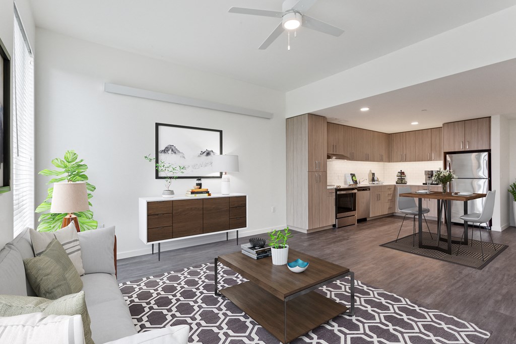 a living area with a couch coffee table and a kitchen in the background