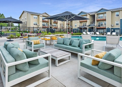 Vancouver, WA, With In-Unit Washer and Dryer - Autumn Grove Apartments - Seasonal Swimming Pool With Cushioned Outdoor Seating, Umbrellas, Lounge Chairs, And Apartment Buildings.
